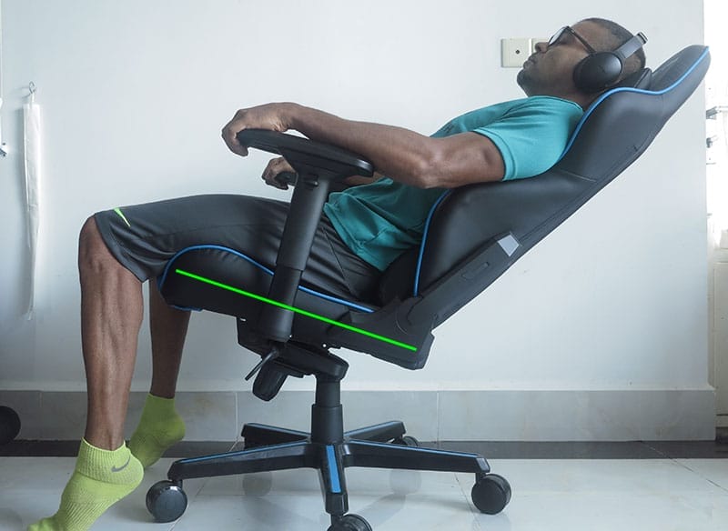 Side view of a man sitting in a gaming chair with a tilted seat