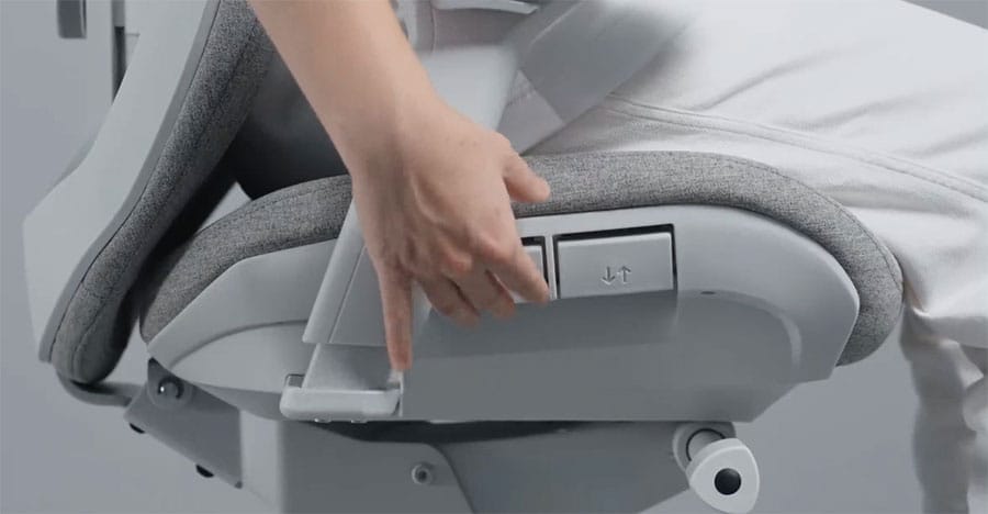 Close-up of a hand operating the Fractal Refine chair’s seat depth adjustment control located on the right side of the seat.