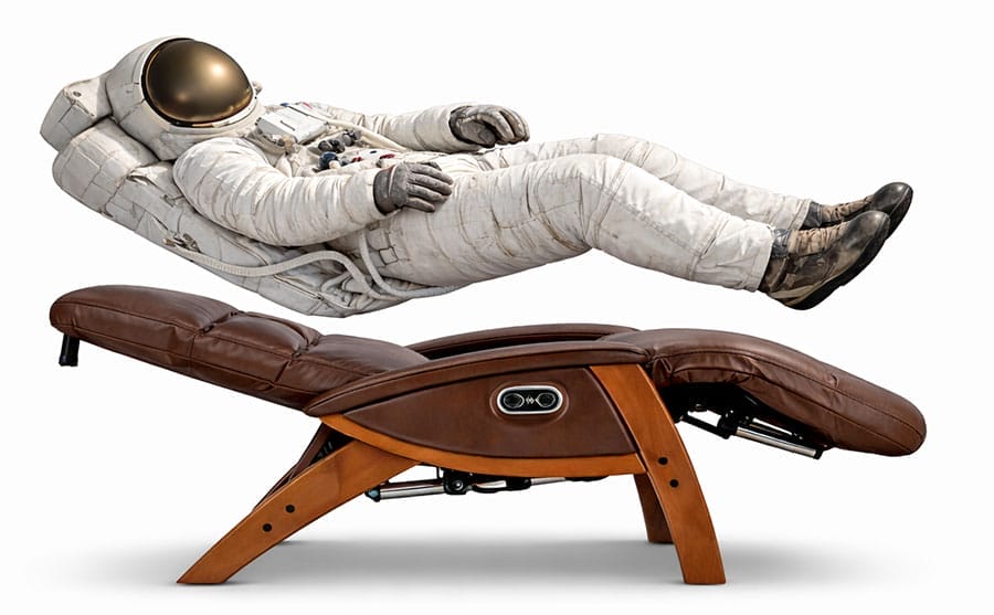 Astronaut floating horizontally above a zero-gravity recliner, aligned to match the chair’s reclined angles, illustrating how zero-gravity seating mimics neutral body posture by supporting the spine, hips, and bent knees.